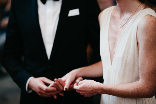 bride with cleavage and groom with classic suit in church holding hands