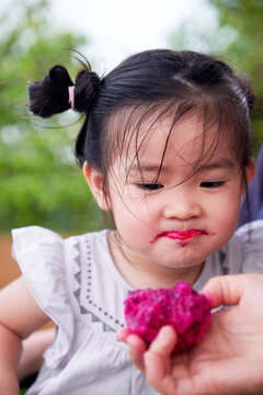 Cute Asian little girls eating dragon fruit. During family holidays