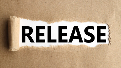 Release. text on white paper over torn paper background.