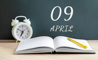April 09. 09-th day of the month, calendar date.  A white alarm clock, an open notebook with blank...