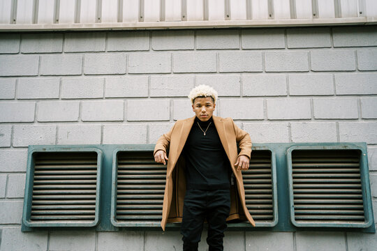 Stylish black man in trendy coat standing on street