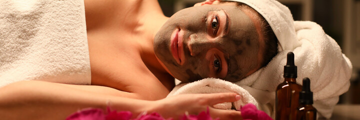 Naklejka premium Woman in white towel with mask on her face do aromatherapy procedures with oils.