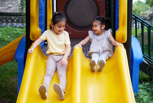 Cute little Asian girls playing on the slide in the farm