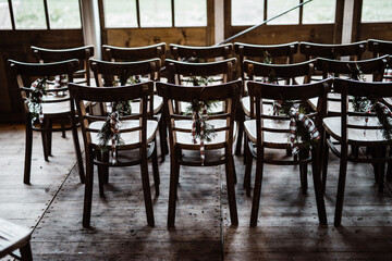 Empty wooden chairs in rows decorated for Christmas with pine leaves and bow