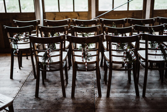 Empty wooden chairs in rows decorated for Christmas with pine leaves and bow