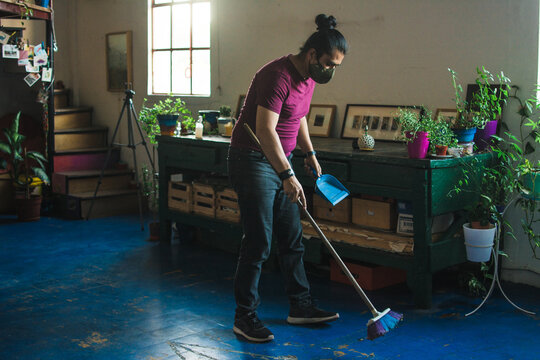 Man sweeping the foor with a mask on