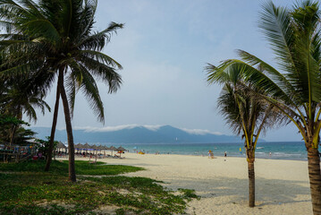 White sand beach with palm trees and mountains in background Da Nang, Vietnam