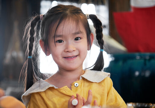Close-up of cute smiling Asian little girl at the bed and breakfast on the trip