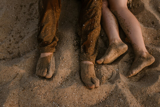 close up of young couples feet covered in sand on the beach