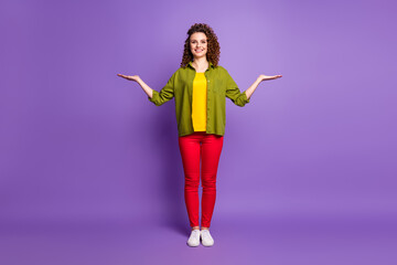 Full size photo of young happy positive girl hold hands in balance advertising product isolated on violet color background