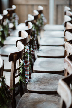 Empty wooden chairs in rows decorated for Christmas with pine leaves and bow