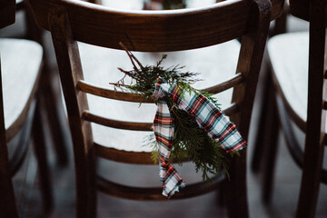 Wooden chairs decorated for Christmas with pine leaves and bow