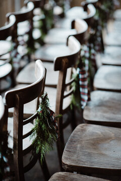 Empty wooden chairs in rows decorated for Christmas with pine leaves and bow