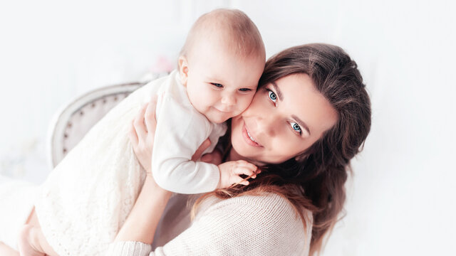 womens or mother day. Happy beautiful young 38 years mother with baby girl in arms. concept of happy family, motherhood. Woman playing with child girl in room.