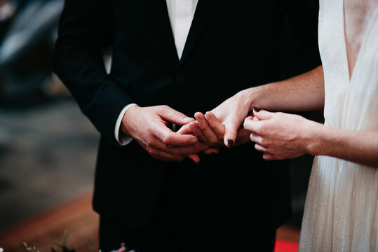 bride with cleavage and groom with classic suit in church holding hands