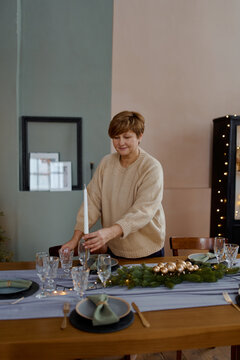 an adult woman at home serves a Christmas table near the Christmas tree at home