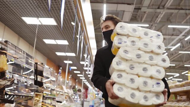 Man walking in medical mask with toilet paper shopping bags during the quarantine coronavirus COVID-19 pandemic in 2019-2021 coronavirus quarantine