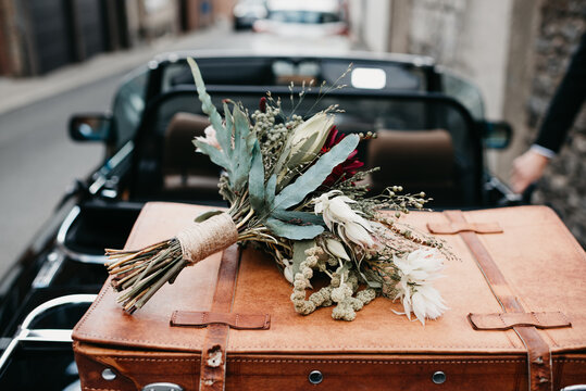 Ready to leave the wedding with a wedding bouquet & suitcase in the car