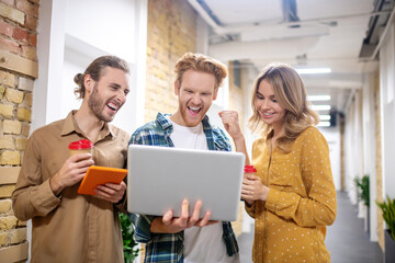 Young coworkers having the coffee break and watching something on a tablet