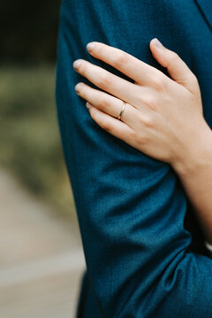 bride with small golden wedding ring touching shoulder of groom