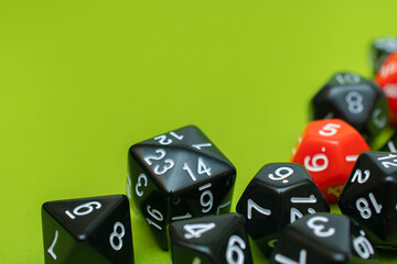 Group of black and red dice D20, D10, D12, D8, D6 on a green background: space for text, top view, concept of role-playing games and games for the whole family at home