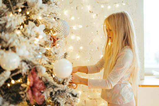 Gentle girl decorating Christmas tree at home
