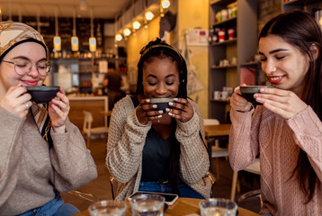 Three young multiethnic female friends spending time together at a coffee shop.