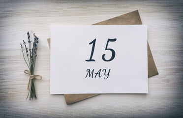 may 15. 15th day of the month, calendar date. White blank of paper with a brown envelope, dry bouquet of lavender flowers on a wooden background. Spring month, day of the year concept