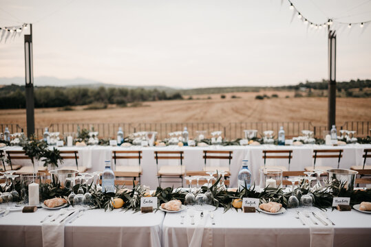 Outdoor wedding reception with white bunting flags and string lights and view on Spanish landscape