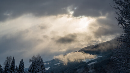 fog, sun and clouds in the morning with fresh snow in the mountains