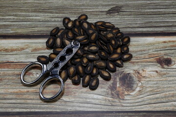 Stainless steel scissors on the pile of baked watermelon seed. Creative tool for cracking melon seeds, little nut and other small stuff. 