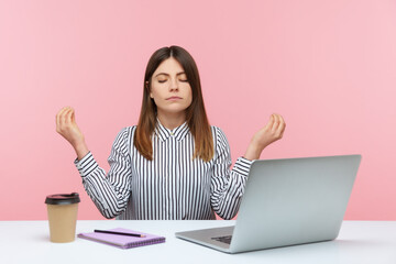 Calm concentrated business woman in striped shirt meditating sitting workplace at home office, resting and relaxing, looking for inspiration. Indoor studio shot isolated on pink background