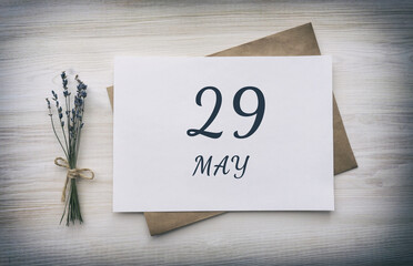 may 29. 29th day of the month, calendar date. White blank of paper with a brown envelope, dry bouquet of lavender flowers on a wooden background. Spring month, day of the year concept