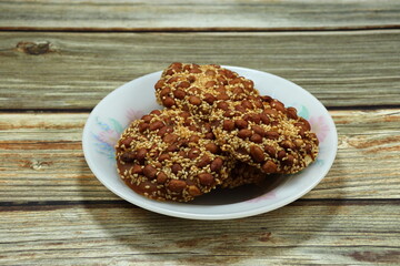 Pile of deep fried crispy peanut mixed with sesame and flour serving on the plate. Famous Traditional Thai sweet dessert in ancient festival and ceremony. 