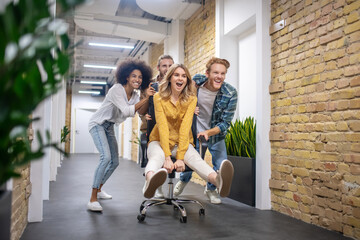 Group of young people riding the chair in the office corridor after a nice day