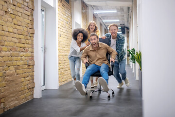 Group of young people riding the chair in the office corridor after a nice day