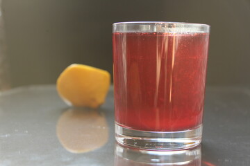 Berry red homemade juice juice compote morse strawberry raspberry on a black grey dark background with a ist for text and a copy of the lemon on the back pan view from the side © Кристина Шоба