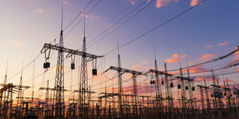silhouette of high voltage power lines against a colorful sky at sunrise.