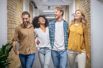 Group of smiling young people walking in the corridor and talking