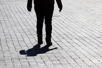 Silhouette and shadow of woman walking on a street. Concept of loneliness, dramatic human life