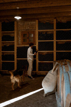 Young winemaker and his dog, inside his winery in the countryside