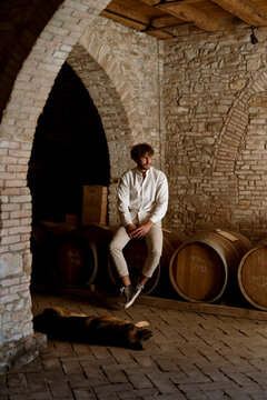 Young winemaker and his dog, inside his winery in the countryside