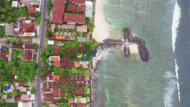Drone top down footage of the Candidasa beach and resort town with jetties in Bali, Indonesia