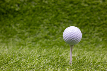 Golf ball is on tee ready to tee off on green grass background