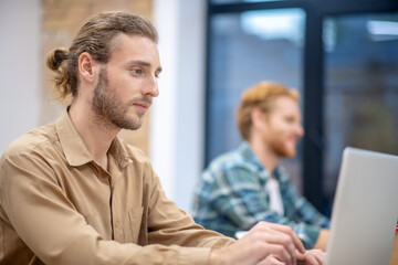 Two male colleagues working on laptops and looking involved