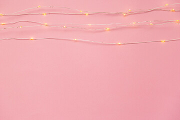 The garland is on. Glowing electric garland on a pink solid background. top view