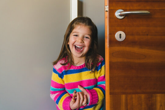 Laughing Little Girl Hiding Behind a Door