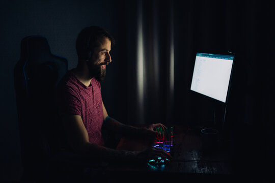Bearded man using computer at night