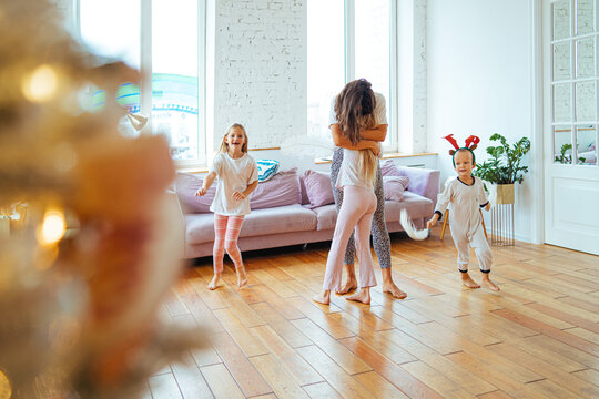 adorable little kids and their mom have fun at home in a room decorated for christmas