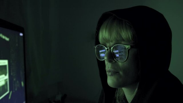 Programmer hacker working on a computer. Code is reflected on his eyeglasses. Guy committing cybercrime. Data thief, internet fraud, darknet and cybersecurity